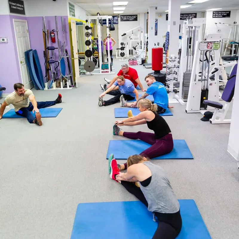 Several All Points clients stretching on blue mats between sets